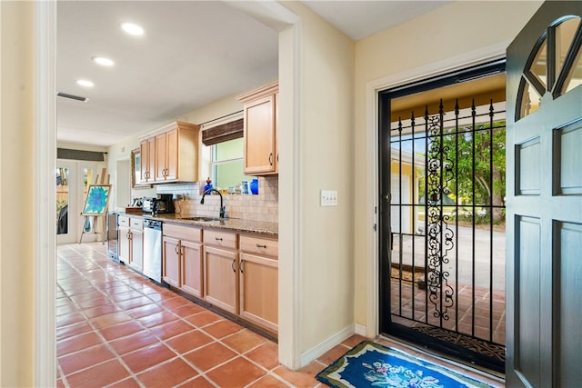 kitchen featuring backsplash, tile patterned floors, stainless steel dishwasher, sink, and light brown cabinets