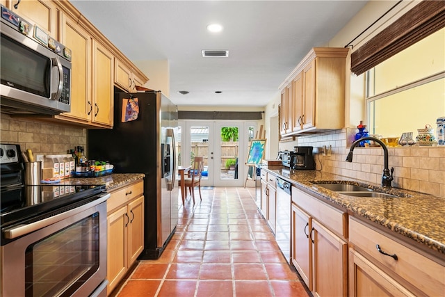 kitchen with tasteful backsplash, appliances with stainless steel finishes, sink, and stone counters