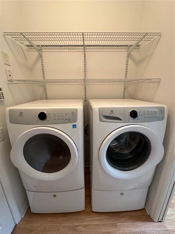 laundry room with laundry area, separate washer and dryer, and light wood-style flooring