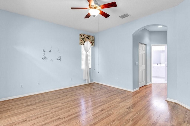 spare room with arched walkways, visible vents, baseboards, a ceiling fan, and light wood-type flooring