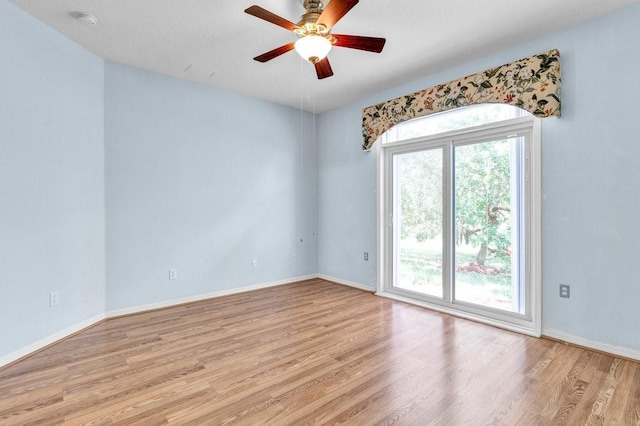 empty room with ceiling fan, light wood finished floors, and baseboards