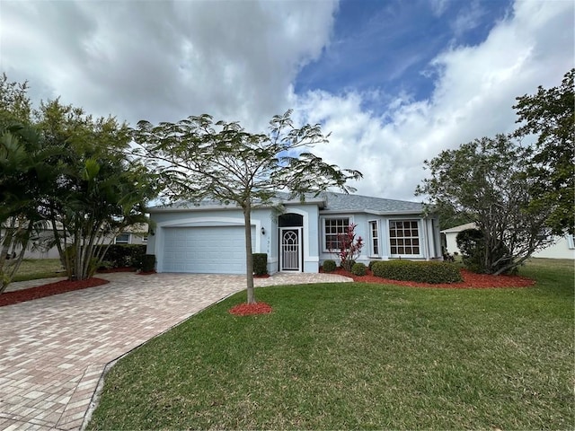 single story home featuring a front lawn, decorative driveway, an attached garage, and stucco siding