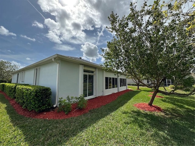 view of side of home featuring a lawn and stucco siding