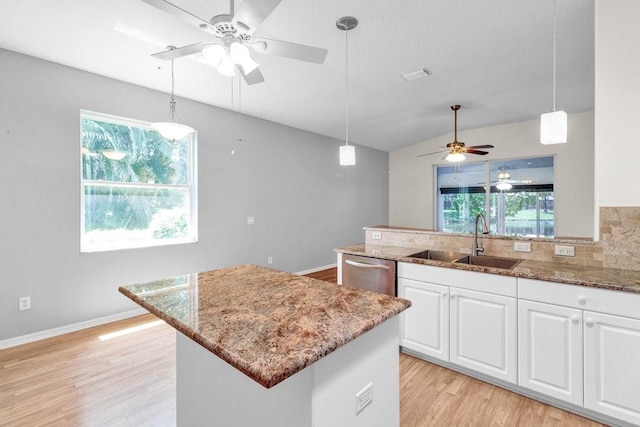 kitchen featuring dishwasher, light stone counters, and a sink