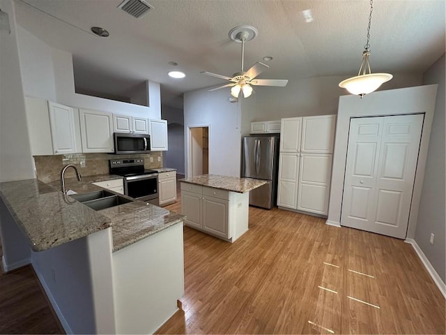 kitchen with a sink, visible vents, appliances with stainless steel finishes, light wood-type flooring, and decorative backsplash