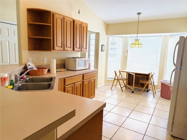 kitchen with pendant lighting, light tile patterned flooring, vaulted ceiling, a sink, and white appliances