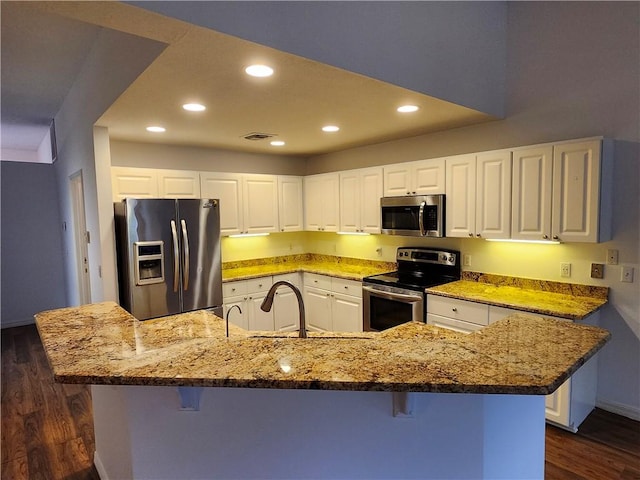 3865 8th Pl, Vero Beach, FL 32960 - kitchen with stainless steel appliances, dark wood-style floors, a breakfast bar, recessed lighting, and light stone counters