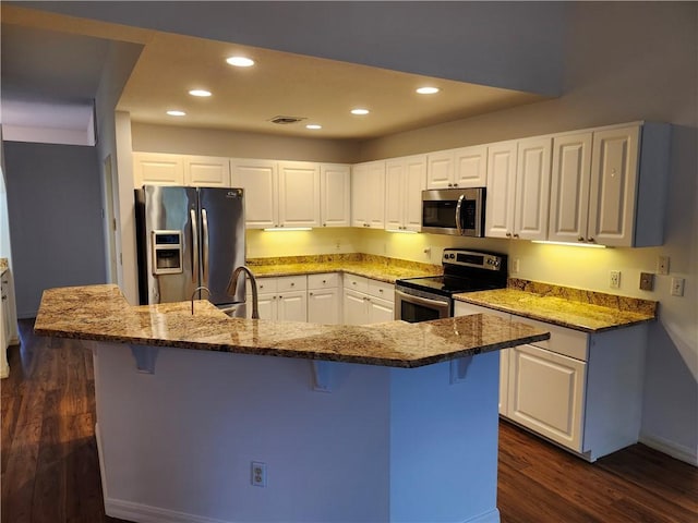 3865 8th Pl, Vero Beach, FL 32960 - kitchen featuring stainless steel appliances, dark wood-style floors, recessed lighting, a kitchen bar, and white cabinets