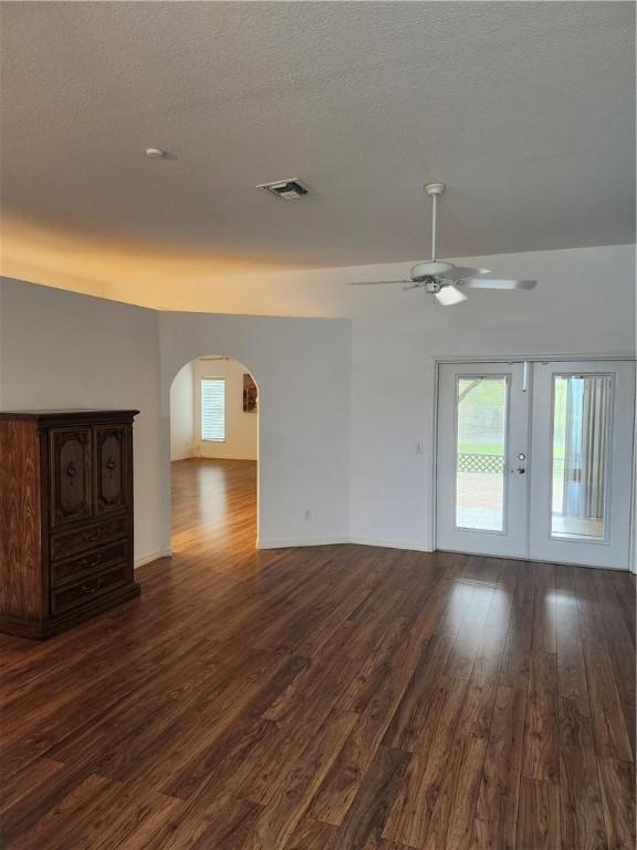 3865 8th Pl, Vero Beach, FL 32960 - unfurnished living room with arched walkways, dark wood-style flooring, a ceiling fan, french doors, and a textured ceiling