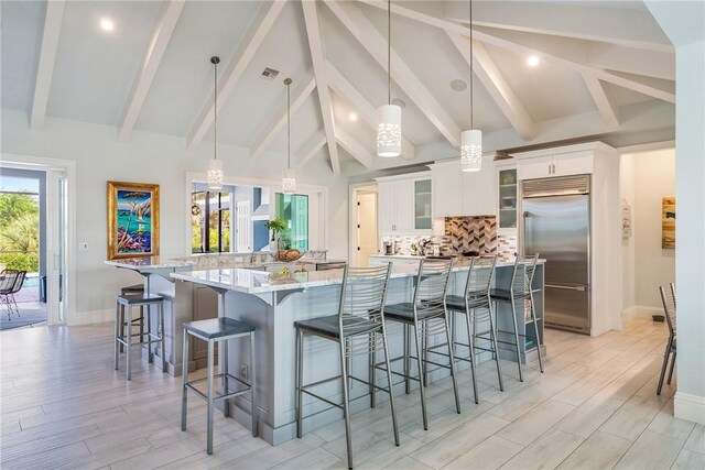 951 W Polo Grounds Dr, Vero Beach, FL 32966 - kitchen with built in fridge, decorative backsplash, a spacious island, white cabinets, and a kitchen bar