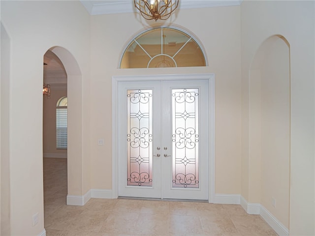 tiled entrance foyer with french doors, a notable chandelier, and crown molding