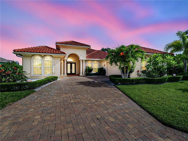 mediterranean / spanish-style home featuring a garage and a yard