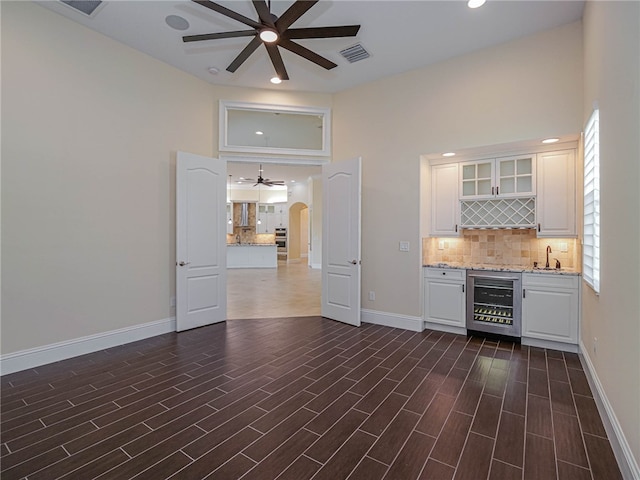 bar with white cabinets, dark hardwood / wood-style floors, beverage cooler, and light stone countertops