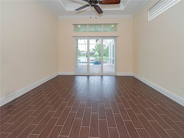 spare room featuring dark hardwood / wood-style flooring, ceiling fan, a tray ceiling, and ornamental molding