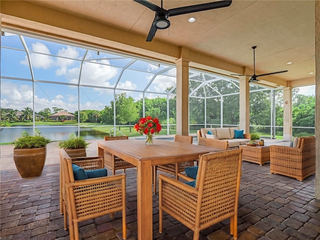 sunroom / solarium featuring a water view and ceiling fan