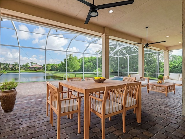 view of patio / terrace featuring an outdoor living space, a water view, a lanai, and ceiling fan