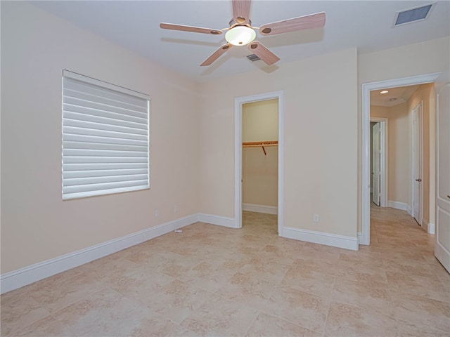 unfurnished bedroom with a closet, a walk in closet, and ceiling fan