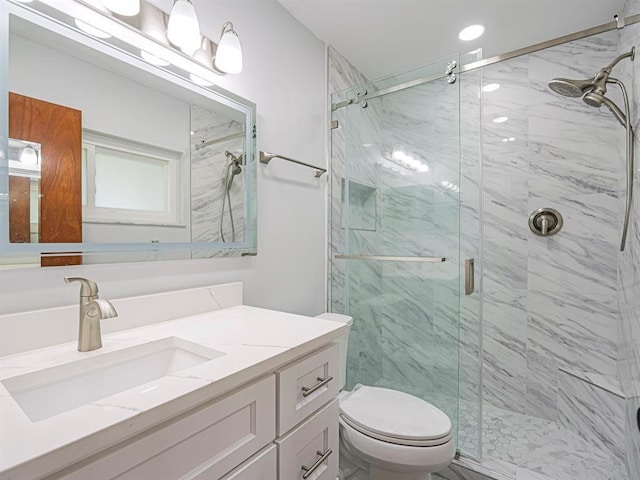 bathroom with vanity, a shower with door, and toilet