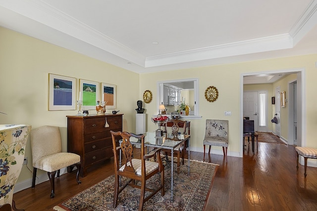 dining space with ornamental molding, dark hardwood / wood-style flooring, and a raised ceiling