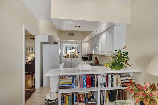 kitchen featuring white appliances, light tile patterned floors, sink, white cabinets, and kitchen peninsula