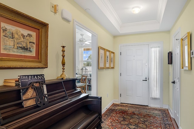 entryway with ornamental molding, ceiling fan, and a tray ceiling