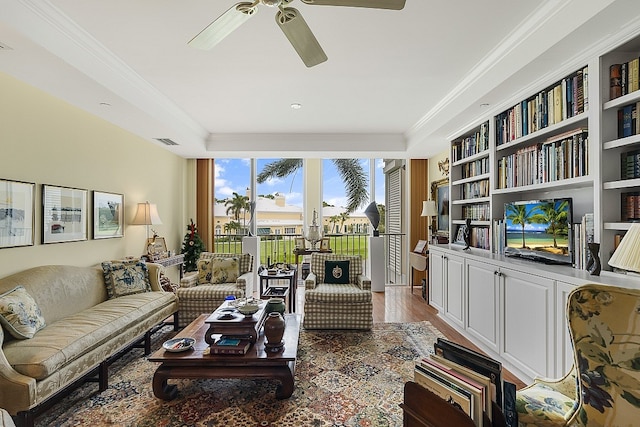 living room featuring wood-type flooring, ceiling fan, and crown molding