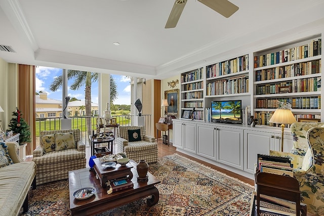 sitting room with wood-type flooring, ceiling fan, and crown molding