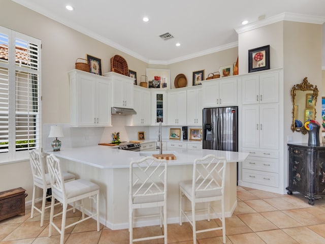 kitchen with a kitchen bar, kitchen peninsula, stainless steel appliances, and white cabinetry