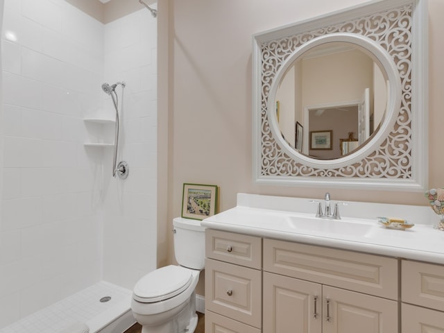 bathroom featuring a tile shower, vanity, and toilet