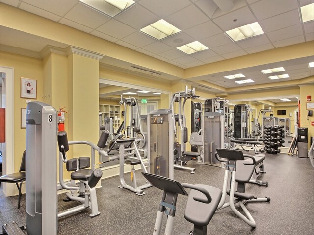 exercise room with ornamental molding and a drop ceiling