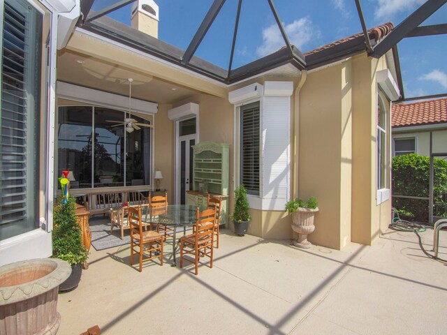 view of patio / terrace with a lanai, a wall unit AC, and ceiling fan