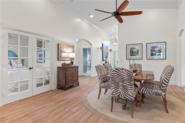 dining space featuring crown molding, high vaulted ceiling, light hardwood / wood-style floors, ceiling fan with notable chandelier, and french doors