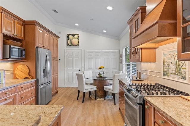 kitchen featuring tasteful backsplash, lofted ceiling, stainless steel appliances, and premium range hood