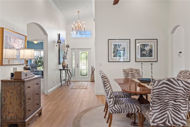 dining area featuring crown molding, high vaulted ceiling, and light hardwood / wood-style floors