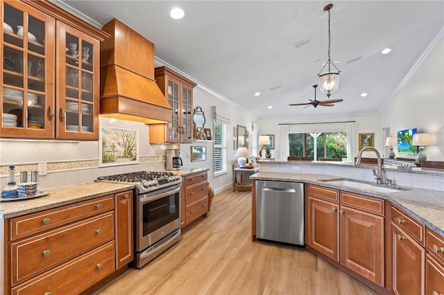 kitchen featuring appliances with stainless steel finishes, sink, ornamental molding, light stone countertops, and custom range hood