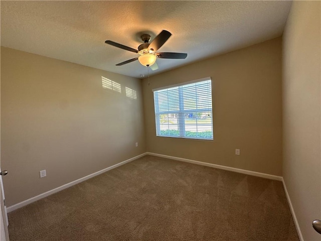 spare room featuring dark colored carpet, a ceiling fan, baseboards, and a textured ceiling