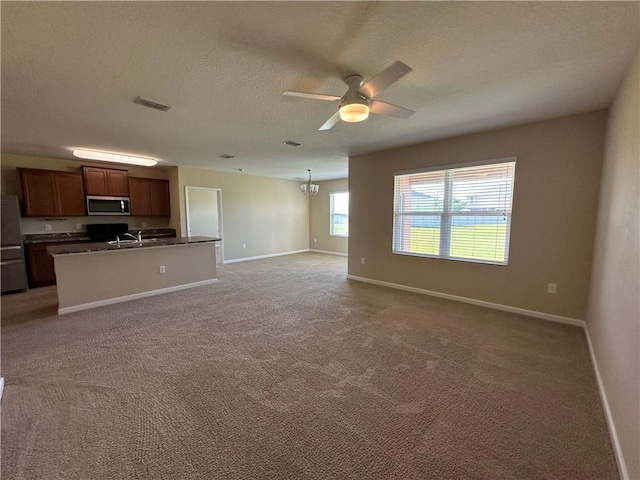 unfurnished living room featuring light carpet, a textured ceiling, ceiling fan with notable chandelier, baseboards, and visible vents