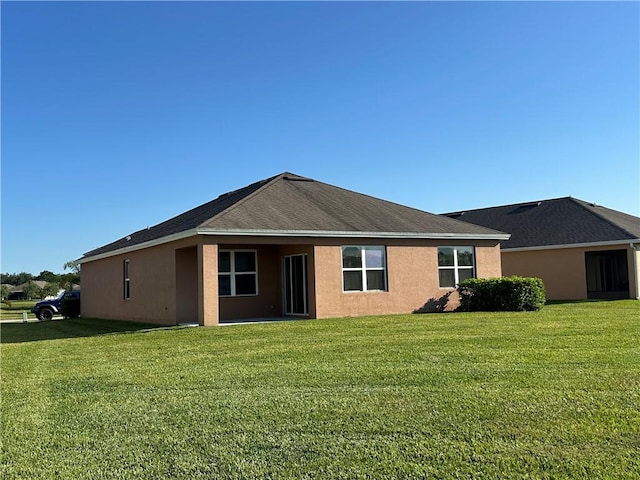 rear view of house with a lawn and stucco siding