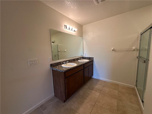 bathroom with a sink, a textured ceiling, and a stall shower