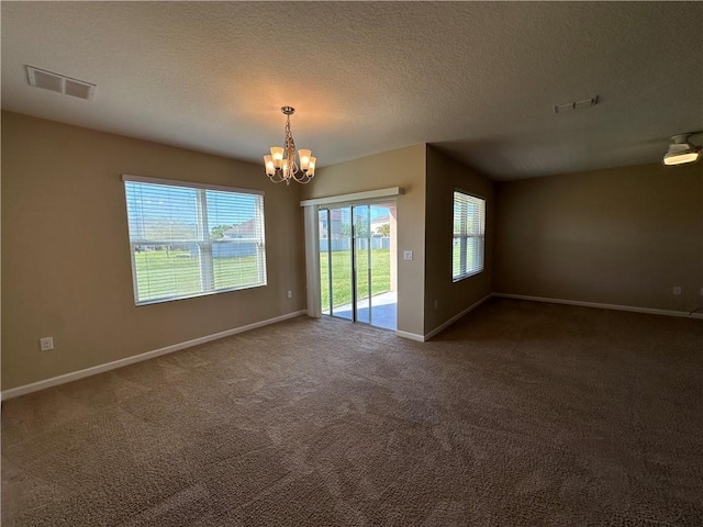 empty room with baseboards, an inviting chandelier, carpet, and visible vents