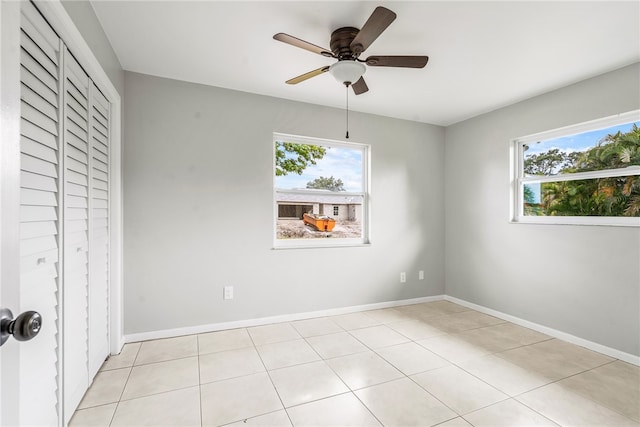 interior space with light tile patterned flooring, multiple windows, ceiling fan, and a closet