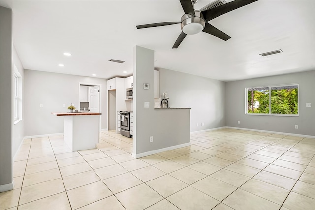 unfurnished living room with ceiling fan, light tile patterned floors, and sink