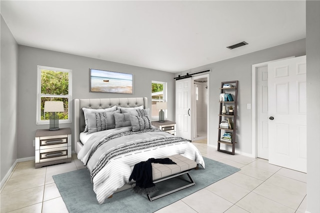 bedroom with a barn door and light tile patterned floors