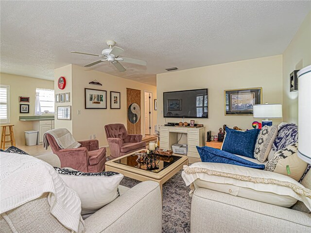 living room with ceiling fan and a textured ceiling