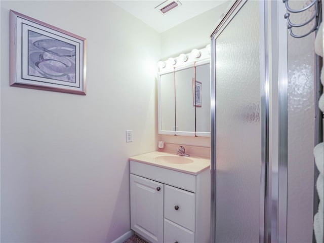 bathroom featuring a shower with door and vanity