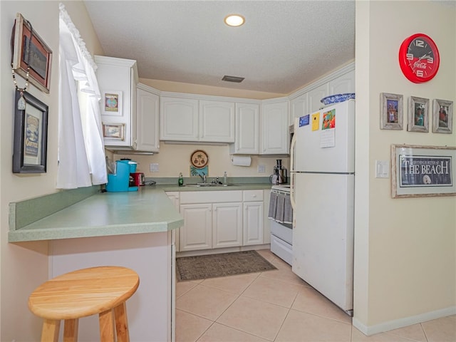 kitchen featuring white appliances, white cabinetry, a breakfast bar, and kitchen peninsula