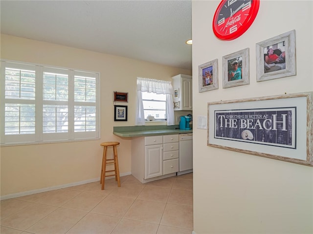 kitchen featuring dishwasher, light tile patterned flooring, and white cabinets