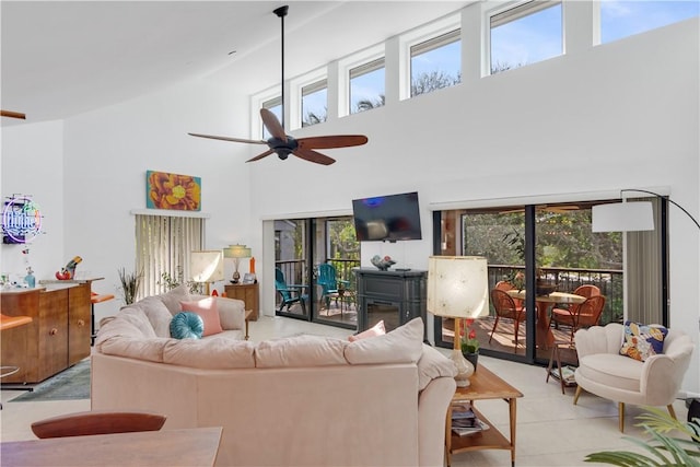 living room with ceiling fan, a towering ceiling, and a healthy amount of sunlight