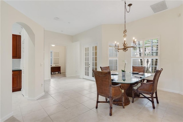 9520 E Maiden Ct, Vero Beach, FL 32963 - dining area featuring arched walkways, a chandelier, light tile patterned flooring, and baseboards