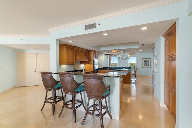 kitchen with a breakfast bar area, crown molding, decorative light fixtures, a textured ceiling, and kitchen peninsula